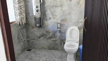 Un baño con piso de mármol, inodoro, ducha y toallero.