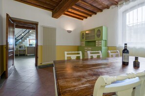 A dining area with a wooden table and chairs, a radiator, and a green cabinet with drawers.