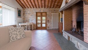 A cozy room with a stone wall, a fireplace, a wooden ceiling, and a tiled floor. - Lovely apartment in villa with A/C, WIFI, pool, TV, balcony and pets allowed, close to San Gimig... (Poggibonsi)