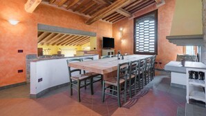 An open-plan kitchen and dining area with a large wooden ceiling, a TV, and a stone fireplace. - Nice apartment in villa with pool, A/C, WIFI, TV and pets allowed, close to San Gimignano (Poggibonsi)