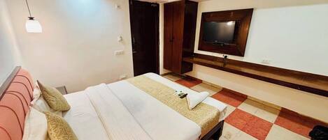 Una habitación de hotel con cama, televisor, ventilador de techo y piso a cuadros.