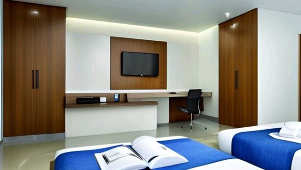 A hotel room with two beds, a desk, a chair, and a TV mounted on the wall. - Hotel Seven Inn (Ahmedabad)