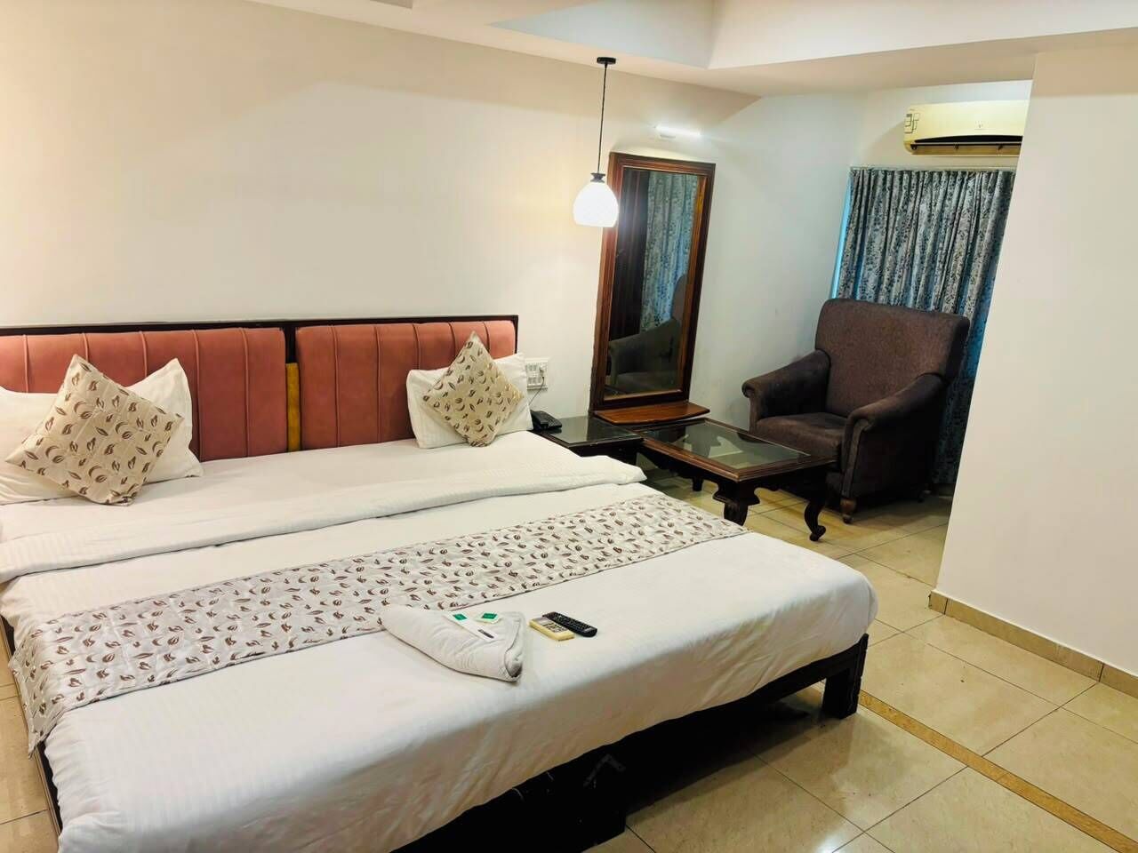 Une chambre d’hôtel avec deux lits, un canapé, une télévision et un appareil de climatisation.
