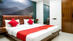 A modern hotel room with a large bed, a mountain view mural, and a wooden door. - Hotel Seven Inn (Ahmedabad)