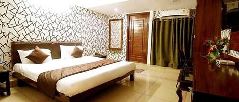 Una habitación de hotel con cama, escritorio, silla, armario y cortina.