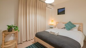 A neatly arranged bedroom with a bed, bedside table, lamp, and a potted plant. - Seiwa Travel Time Sunahama (Osaka)