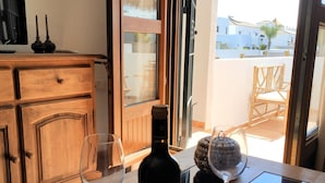 Una habitación con un armario de madera, una mesa con una botella de vino y dos copas de vino, y vistas a un edificio a través de una puerta de cristal.