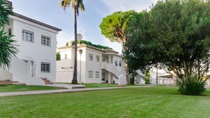 A white building with a tiled roof, a palm tree, and a well-maintained lawn. - Pinar 12 14334 in Chiclana (Chiclana de la Frontera)