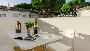 A white table with a magazine, a bottle of wine, and a candle on a balcony. - Pinar 12 14334 in Chiclana (Chiclana de la Frontera)