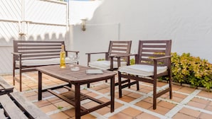 A patio with a wooden table and four chairs, a bottle of wine, and two glasses. - Duplex El Manantial 16345 (El Puerto de Santa Maria)