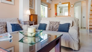 A living room with a glass coffee table, two sofas, a side table with a lamp, and a painting on the wall. - Duplex El Manantial 16345 (El Puerto de Santa Maria)