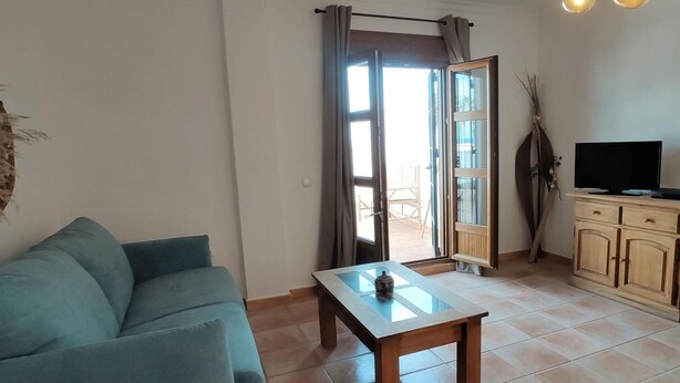 Una sala de estar con sofá, mesa de centro, televisor y mueble.