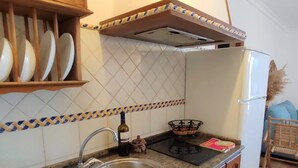 Una cocina con un lavamanos de acero inoxidable, una botella de vino y una cesta en la encimera.