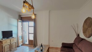 A living room with a wooden TV stand, a brown sofa, a wooden coffee table, and a unique light fixture. - Rezon 1 5012 in Conil de la Frontera (Conil de la Frontera)