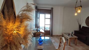 Zona de menjador amb una taula rodona, cadires, un vas blau i una planta decorativa.