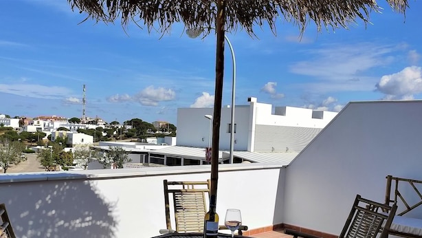 A rooftop terrace with a table and two chairs, a glass of wine, and a view of the cityscape. - Rezon 1 5012 in Conil de la Frontera (Conil de la Frontera)