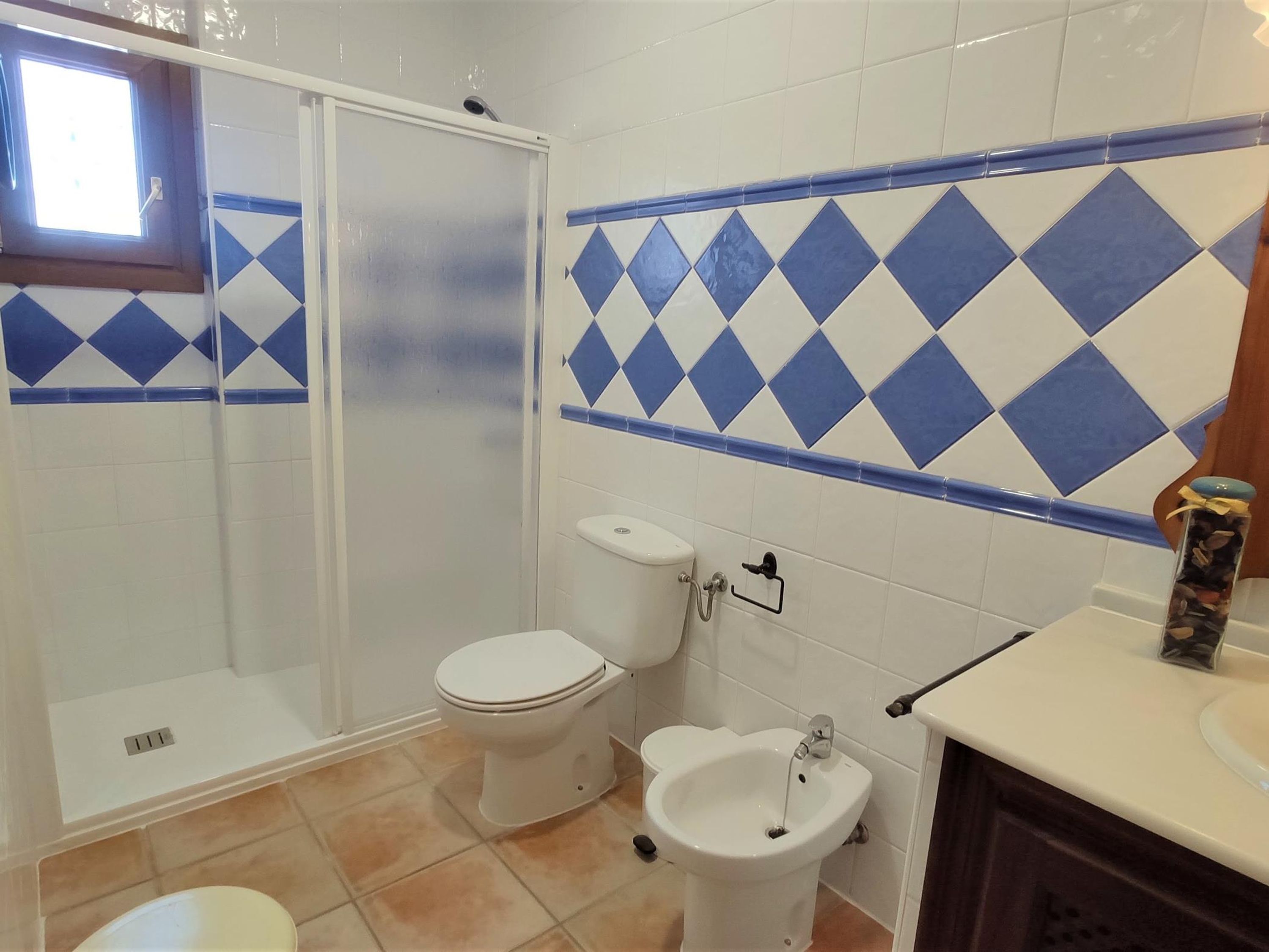 A bathroom with a shower, toilet, bidet, and sink.