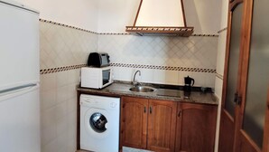 A compact kitchen with a washing machine, a microwave, a sink, and wooden cabinets. - Rezon 1 5012 in Conil de la Frontera (Conil de la Frontera)