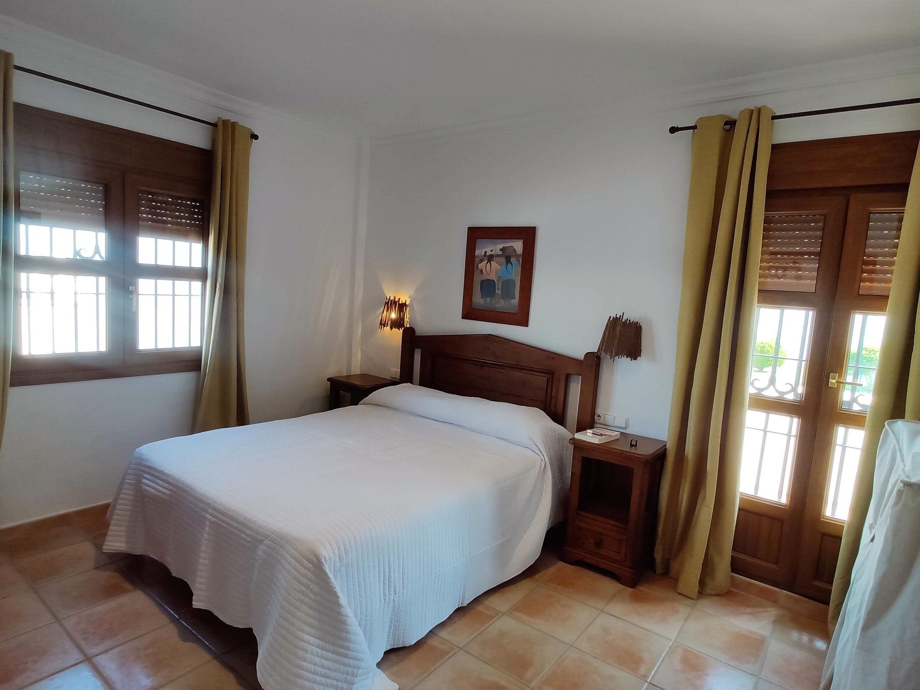 Habitació d'hotel amb un llit, una tauleta de nit, una làmpada penjada a la paret i un quadre.
