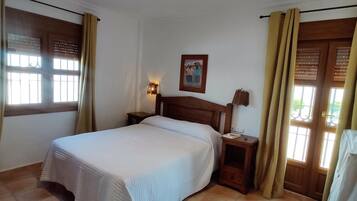 Habitació d'hotel amb un llit, una tauleta de nit, una làmpada penjada a la paret i un quadre.