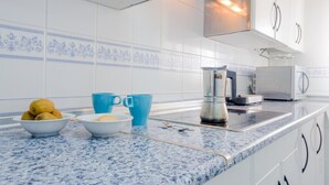 A kitchen with white cabinets, a granite countertop, and blue decorative tiles. - Apartamento La Capillita de Sanl car 15244 (Sanlucar de Barrameda)
