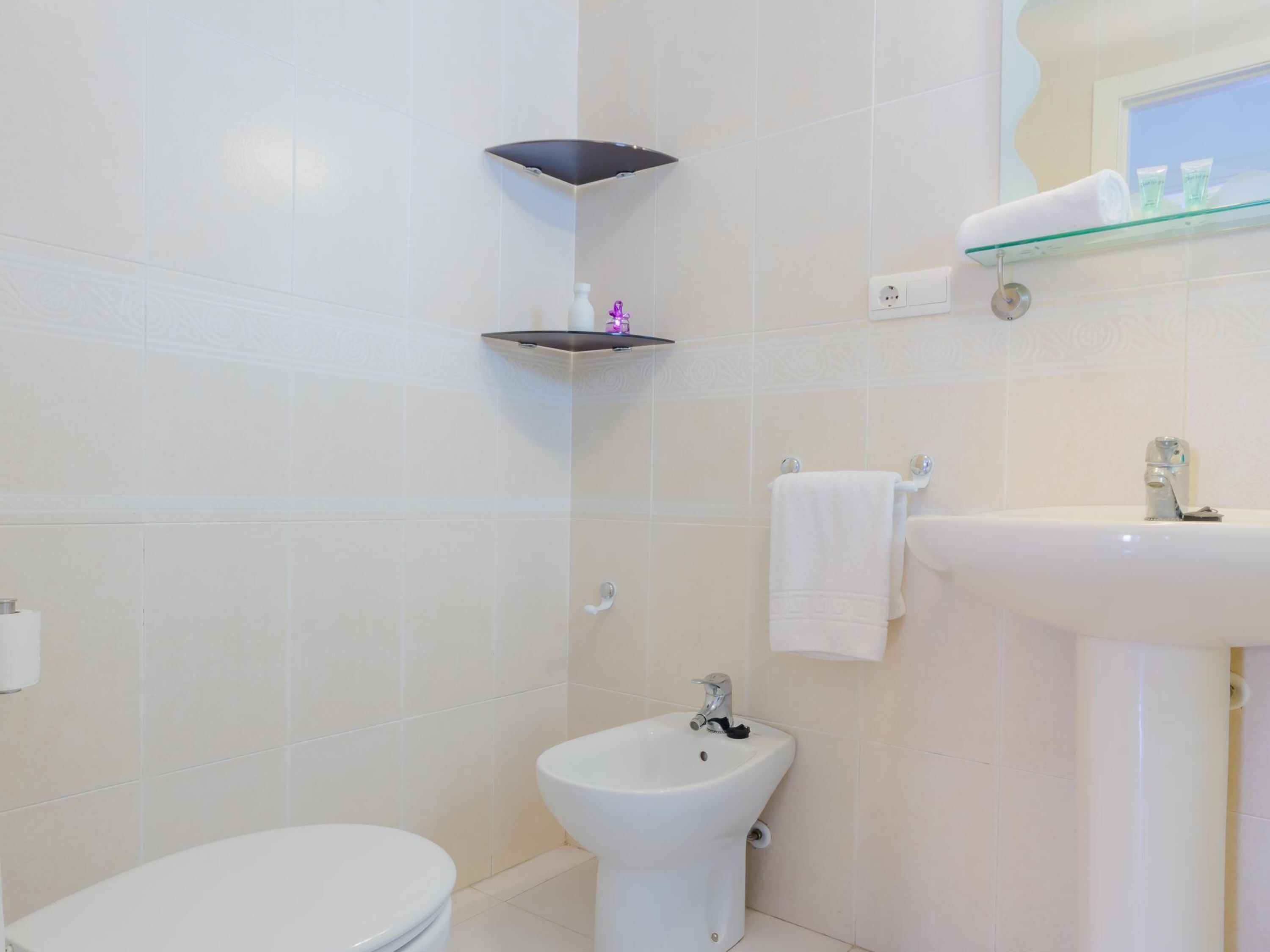 A bathroom with a toilet, bidet, and a sink.