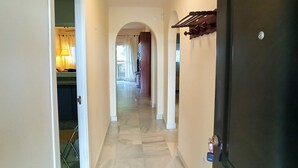 A hallway with a marble floor, a door on the right, and a view into a room with a lamp. - Dunas II 2D 15436 in El Puerto de Santa Mar a (El Puerto de Santa Maria)