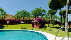 A swimming pool with clear blue water, surrounded by well-maintained grass and trees. - Dunas II 2D 15436 in El Puerto de Santa Mar a (El Puerto de Santa Maria)