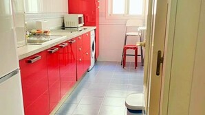 Una cocina con armarios rojos, un microondas y una lavadora.