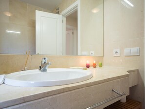 A bathroom with a white sink, a mirror, and a wooden shelf. - Dunas II 13382 in El Puerto de Santa Mar a (El Puerto de Santa Maria)