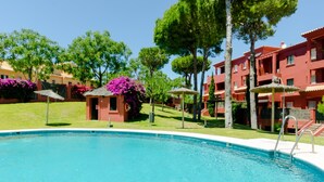 A swimming pool with a lifeguard station, surrounded by red buildings and green trees.