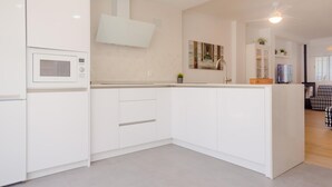 Uma cozinha moderna com armários brancos, micro-ondas e ventilador de teto.