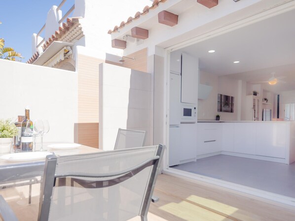 A modern kitchen with white cabinets, a microwave, and a sink.