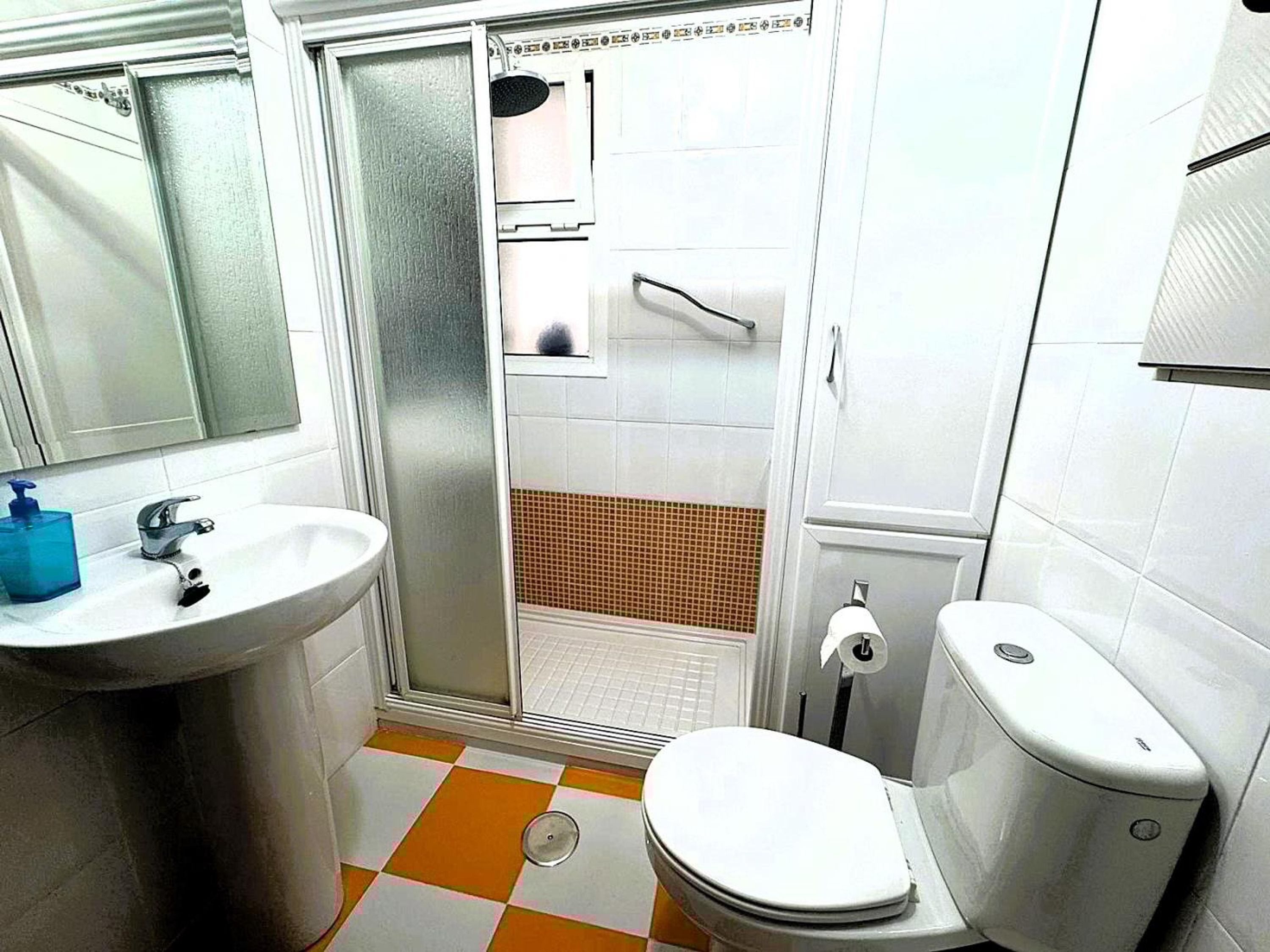 A bathroom with a white sink, toilet, and shower area.