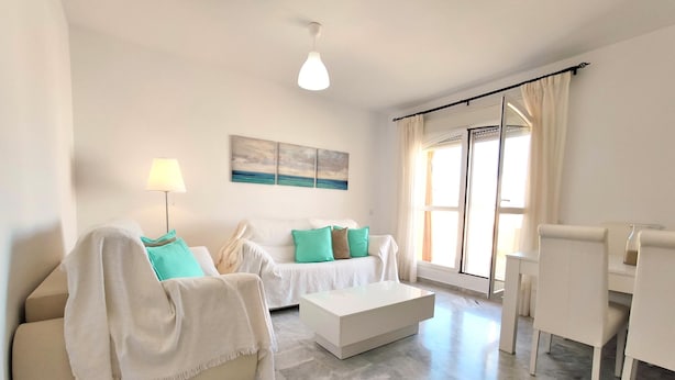 Una sala de estar moderna con un sofá, una mesa de centro, una lámpara y un cuadro en la pared.