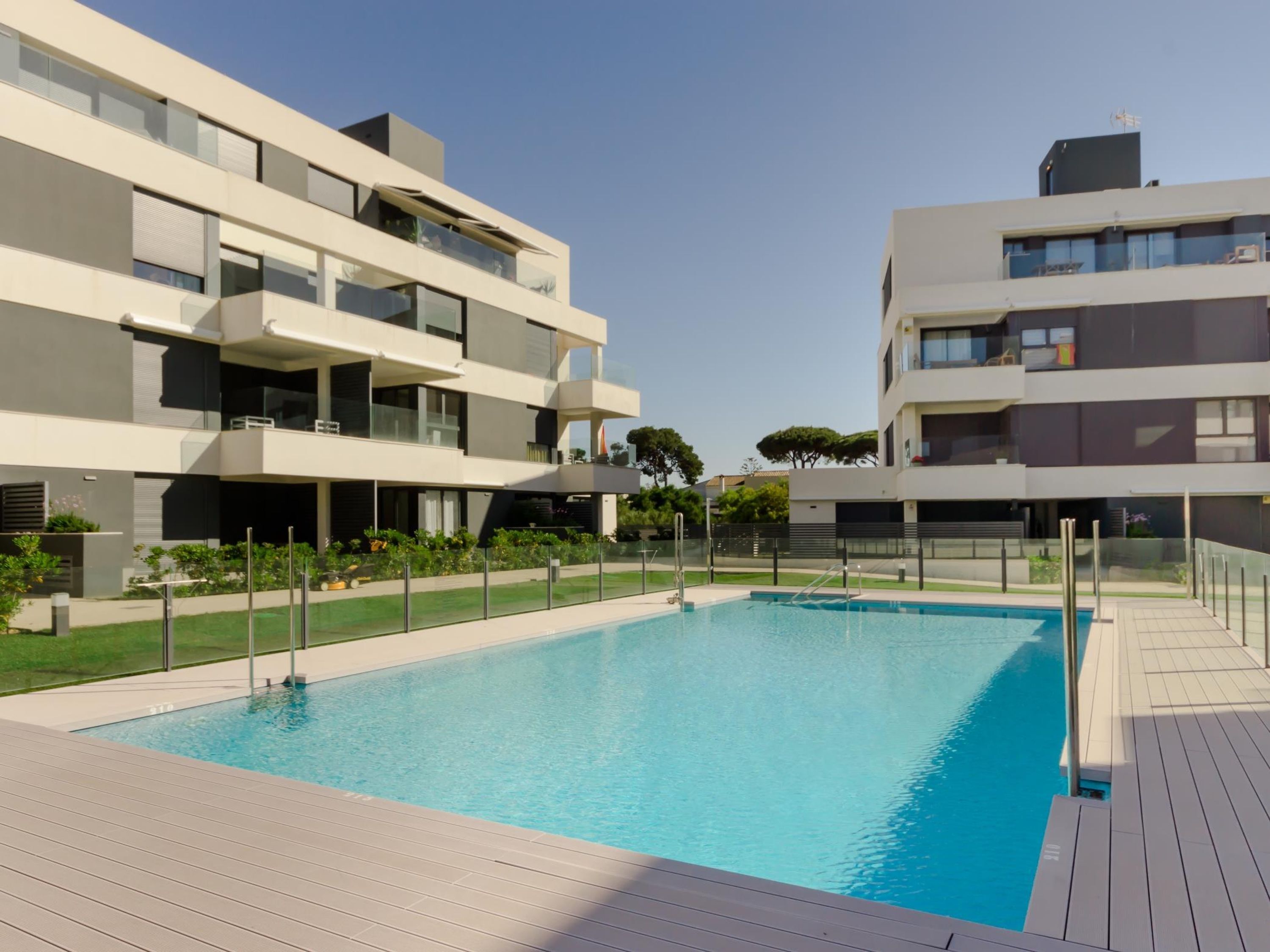 A modern apartment complex with a swimming pool, balconies, and a well-maintained garden.