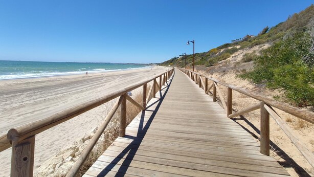 A wooden boardwalk leading to a beach with clear skies. - Bah a Blanca II 18923 (El Puerto de Santa Maria)