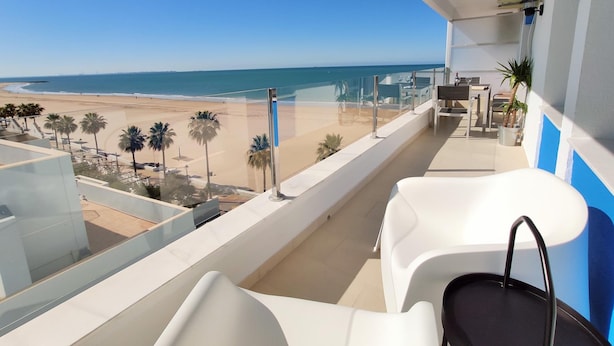 A balcony with a view of the beach, white chairs, and a small table. - Sea Views Rota 24397 (Rota)