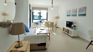 Ein modernes Wohnzimmer mit einer Couch, einem Fernseher, einem Essbereich mit Stühlen und Kunstwerken an der Wand.