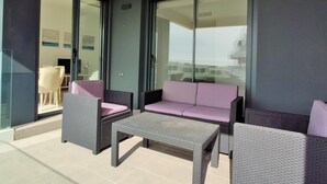 Ein Balkon mit Korbmöbeln, darunter eine Couch und Stühle, sowie ein Tisch.