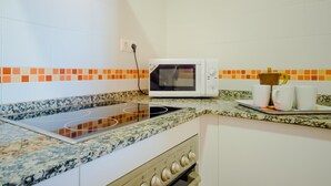 Een keuken met een magnetron, fornuis en een betegelde spatwand.
