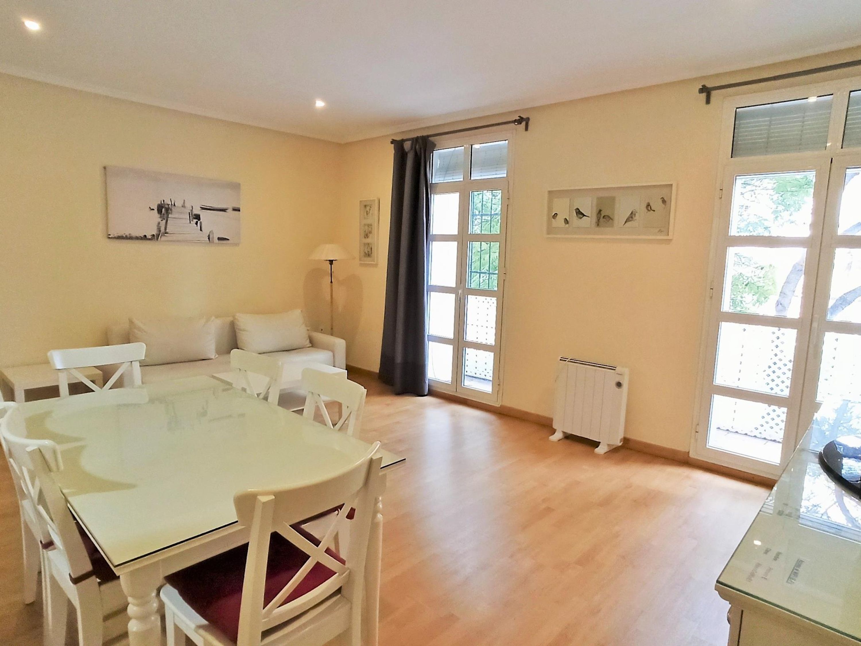 A spacious room with a dining table and chairs, a sofa, and a radiator.