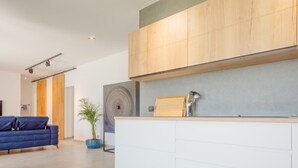 Eine moderne Küche mit Holzschränken, einer weißen Arbeitsplatte und einem großen Wandkunstwerk.