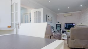 Una sala de estar moderna con comedor, un sofá, un televisor y una chimenea.