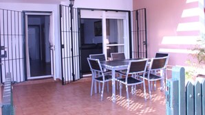 A patio with a table and chairs, a sliding glass door, and a view of the interior. - Balconera 2 16607 in Chiclana (Chiclana de la Frontera)
