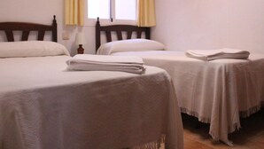 A room with two single beds, each with a wooden headboard and white bedding. There is a window with yellow curtains, and a small table with a lamp beside the window. - Balconera 2 16607 in Chiclana (Chiclana de la Frontera)