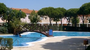 A swimming pool with a bridge, surrounded by trees and buildings. - Balconera 2 16607 in Chiclana (Chiclana de la Frontera)