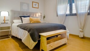A bedroom with a bed, bedside table, lamp, and a window with curtains.