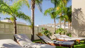 A poolside area with sun loungers and palm trees.
