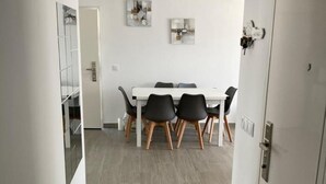 A modern dining area with a white table and black chairs, a wooden floor, and abstract wall art. - Villa El Lagar 14238 (Chiclana de la Frontera)